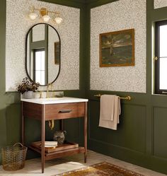 a bathroom with green walls and a white sink under a round mirror on the wall