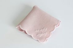 a pink handkerchief with the words baby on it and scalloped edges in white embroidery