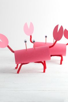 two pink objects with pins sticking out of them sitting on top of a white table