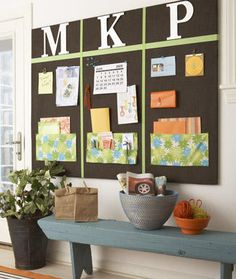 a bulletin board on the wall next to a potted plant and other items sitting on a bench