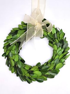 a green wreath with white ribbon hanging on a wall