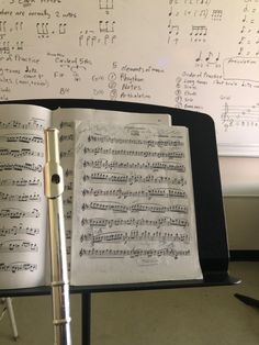 an open book with music notes written on it and a pen in the foreground