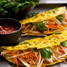 two tortillas with shredded carrots and cilantro on the side next to a bowl of salsa