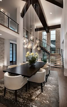 a dining room table with white chairs and chandelier hanging from it's ceiling