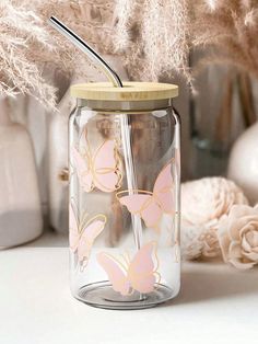 a glass jar with a straw in it sitting on a table next to some flowers