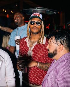 a man with dreadlocks and sunglasses standing next to another man at a party