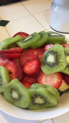 a white plate topped with sliced kiwis and strawberries