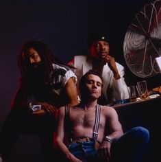 a group of young men sitting next to each other in front of an air fan