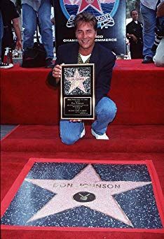 a man kneeling down next to a star on the hollywood walk of fame