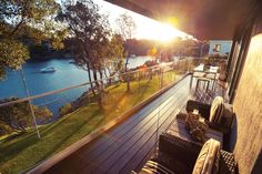 the sun shines brightly on an outdoor deck with chairs and tables overlooking a body of water