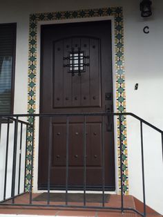 the front door to a house with decorative tiles on it and wrought iron railings