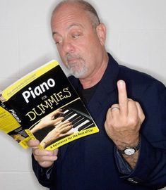 a man holding up a book in front of his face and making the peace sign