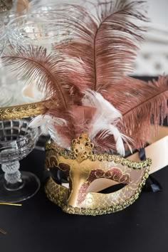 a masquerade mask and some feathers on a table