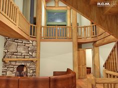 a living room filled with furniture next to a stone wall and wooden staircase leading up to the second floor