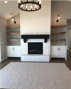 an empty living room with a fireplace and shelves