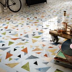 the floor is covered in colorful tiles and has a wooden table with bottles on it