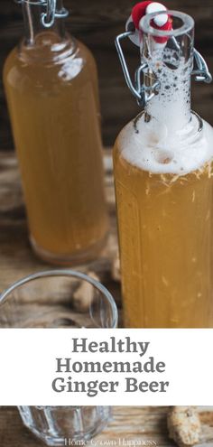 two glass bottles filled with ginger beer sitting on top of a wooden table next to bread