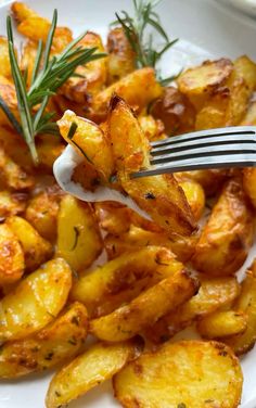 a fork with some food on top of it next to potato wedges and sprigs