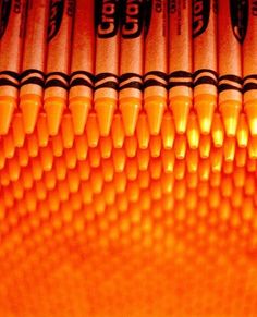 many orange crayons are lined up together