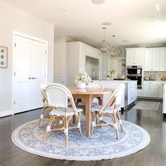 a dining room table with chairs and a rug on the floor in front of it