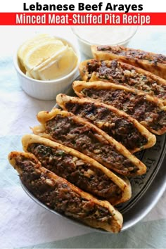 an image of meat stuffed pita breads on a plate with lemon wedges