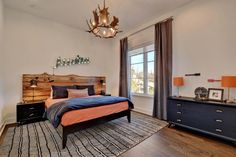 a bed room with a neatly made bed next to a dresser and a large window