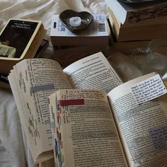 an open book sitting on top of a bed next to two wine glasses and books