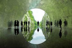 people are standing in the middle of a tunnel with water and trees on both sides