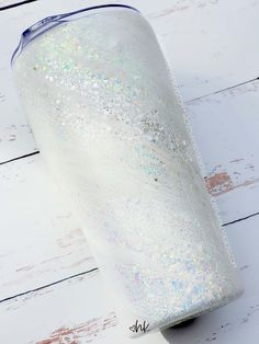 a white glittered cup sitting on top of a wooden table