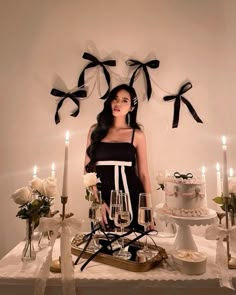 a woman standing in front of a table with cake and wine glasses on top of it