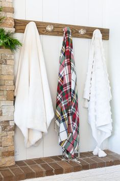 two white and red towels hanging on a brick wall next to a fireplace with potted plants