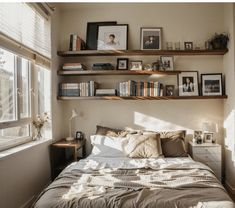 a bed sitting in a bedroom next to a window with books on the shelves above it