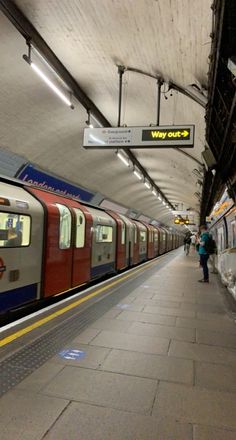 a subway train pulling into the station with people waiting