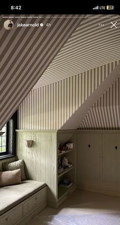 an attic bedroom with striped walls and built - in bookshelves is seen on the phone