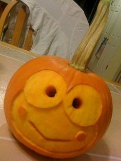 an orange pumpkin with a smiley face drawn on it's side sitting on a table