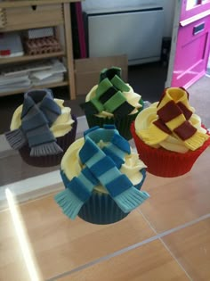 four cupcakes with different colored icing on them sitting on a counter top