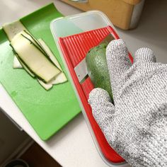 a pair of gloves is sitting next to a cutting board with vegetables on it and a knife