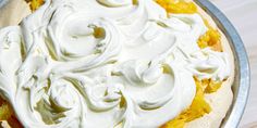 a pie topped with whipped cream on top of a metal pan next to a wooden table