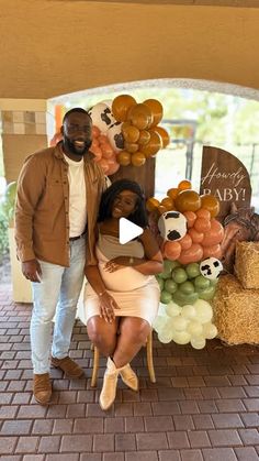 a man and woman standing next to each other in front of a display with balloons