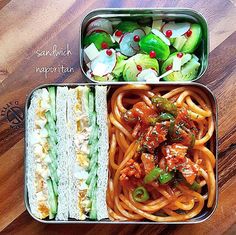 two tins filled with food sitting on top of a wooden table next to each other