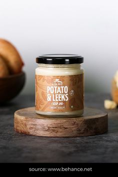 a jar of potato and leeks soup on a wooden board next to some bread