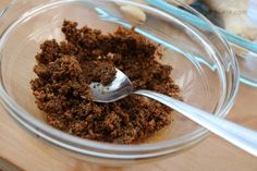 a glass bowl filled with brown stuff and a silver spoon in the bowl next to it