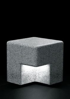 an object made out of concrete sitting on top of a black surface in the dark