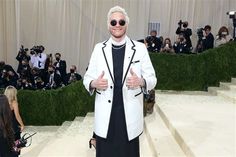 a man with white hair and sunglasses giving the thumbs up sign in front of a group of people