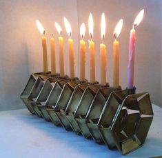 a row of lit candles sitting next to each other on top of a white table