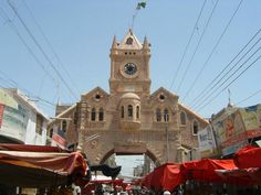 an old building with a clock on it's face in the middle of a street