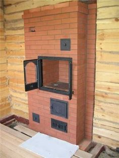 a brick oven sitting on top of a wooden floor next to a wall covered in wood planks