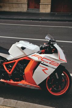 an orange and white motorcycle parked on the street