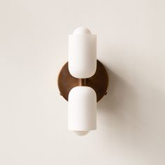 two lights are on the wall next to each other, one is white and the other is brown