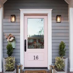 a pink front door with two planters on either side and the number 16 painted on it